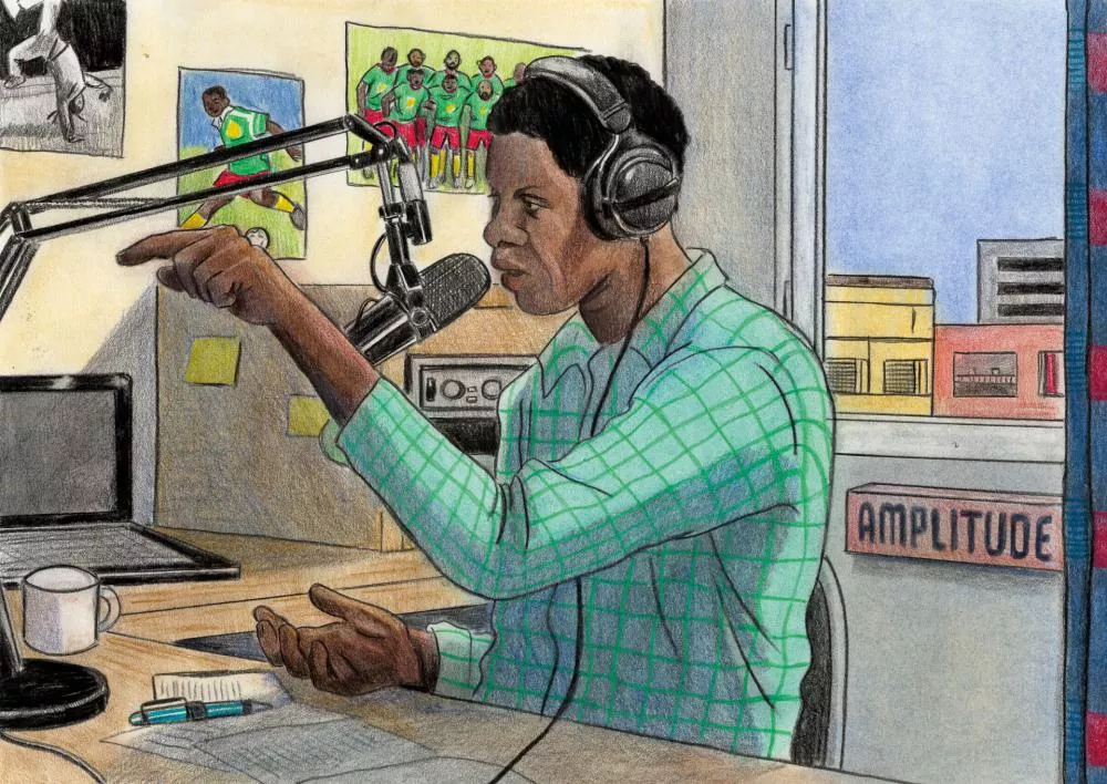 Un homme portant un casque parle dans un microphone dans un studio de radio. Il est entouré d'équipements tels qu'un ordinateur portable et des notes. Des affiches de football sont accrochées au mur derrière lui.