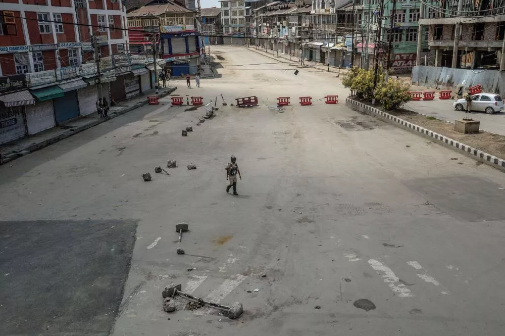 Une rue vide avec des barrières rouges, des bâtiments de chaque côté, et une personne marchant au centre.