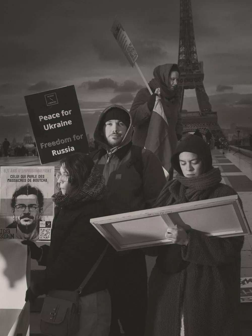 Des personnes manifestent devant la Tour Eiffel avec des pancartes demandant la paix pour l'Ukraine et la liberté pour la Russie. Une affiche mentionne "8,5 ans d'emprisonnement" et "massacres de Boutcha".