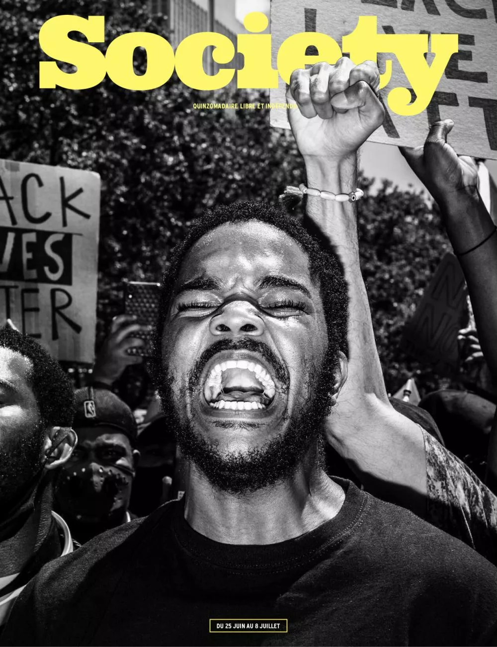 Un homme crie en levant le poing lors d'une manifestation. En arrière-plan, on voit des pancartes avec des messages revendicatifs. Le titre du magazine "Society" est en jaune en haut de l'image.