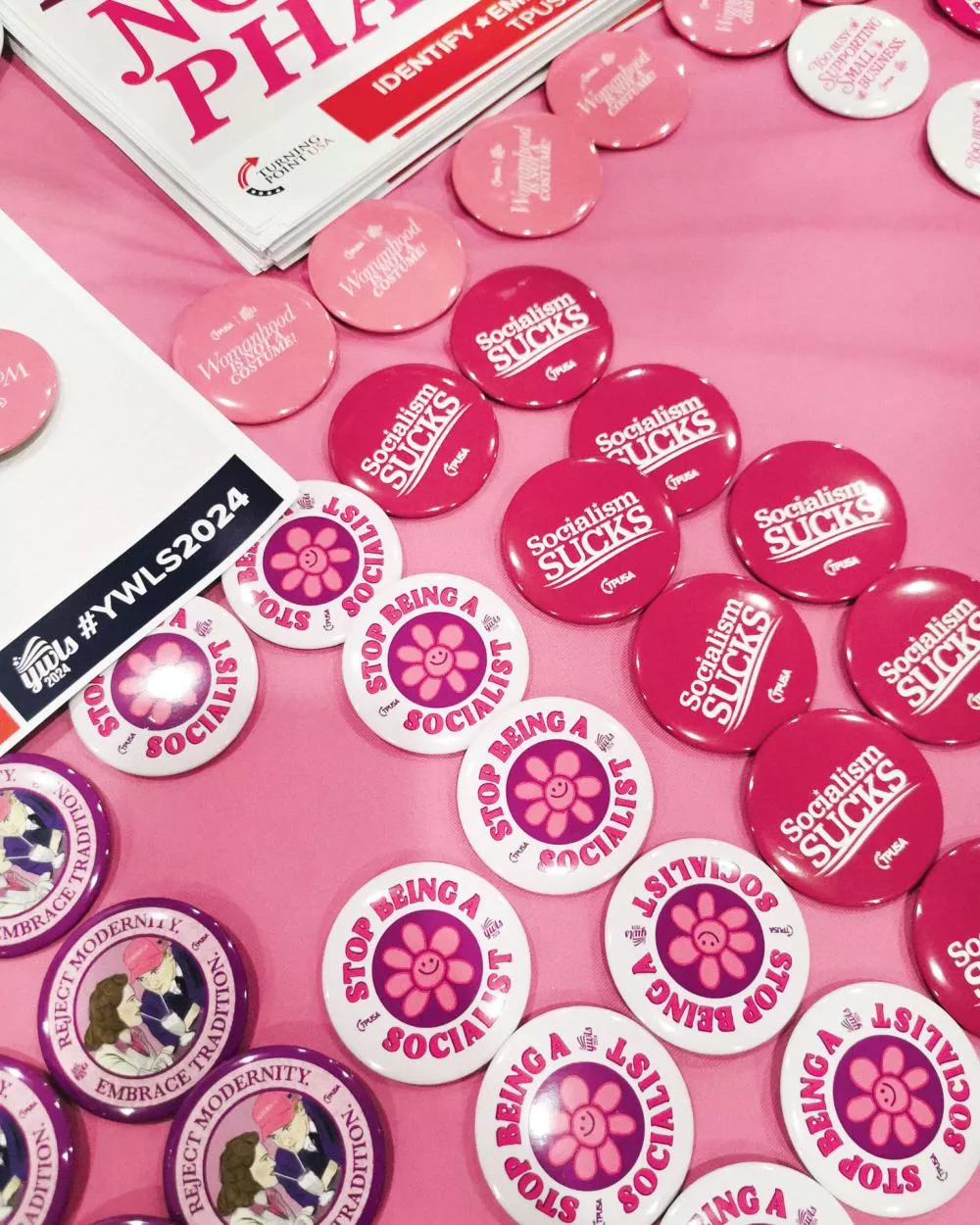 L'image montre des badges avec des slogans anti-socialistes tels que "Socialism Sucks" et "Stop Being a Socialist", ainsi que des messages promouvant la tradition.
