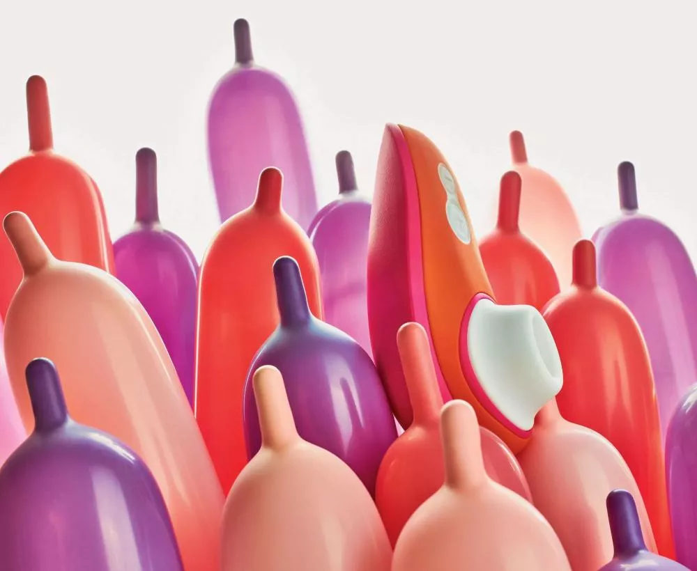L'image montre un groupe de ballons colorés en forme de tétons avec un objet orange et blanc au centre.