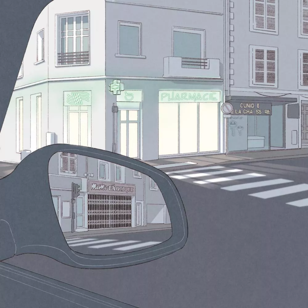 Un rétroviseur de voiture reflète une rue avec des bâtiments, dont une pharmacie éclairée et une boutique fermée appelée "Mimi Exotique".