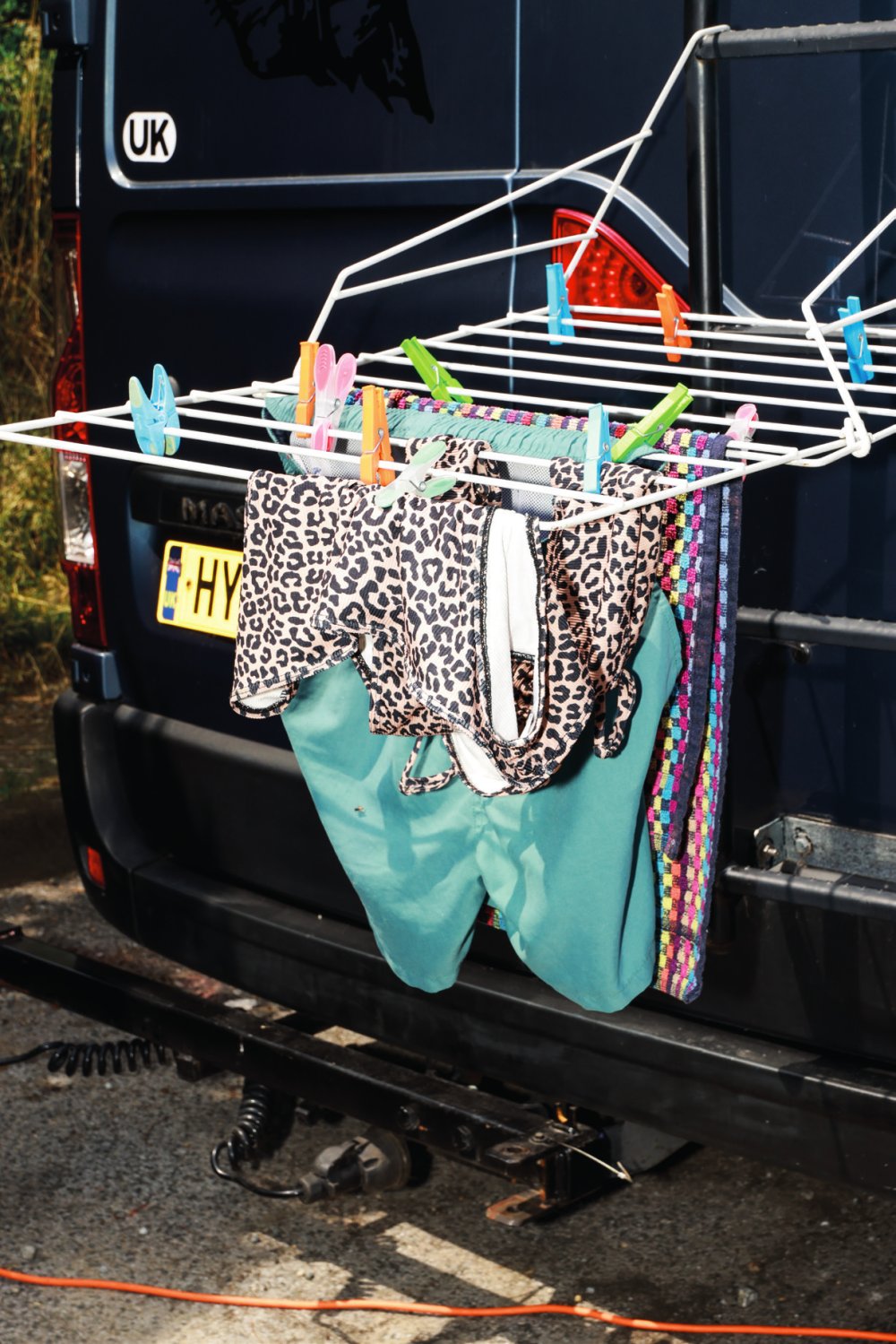 Un étendoir à linge est attaché à l'arrière d'un véhicule, avec des vêtements colorés et des pinces à linge.