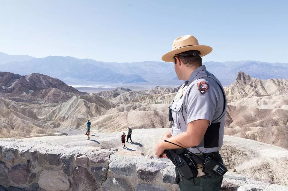 Un garde forestier surveille des visiteurs dans un paysage désertique et montagneux.