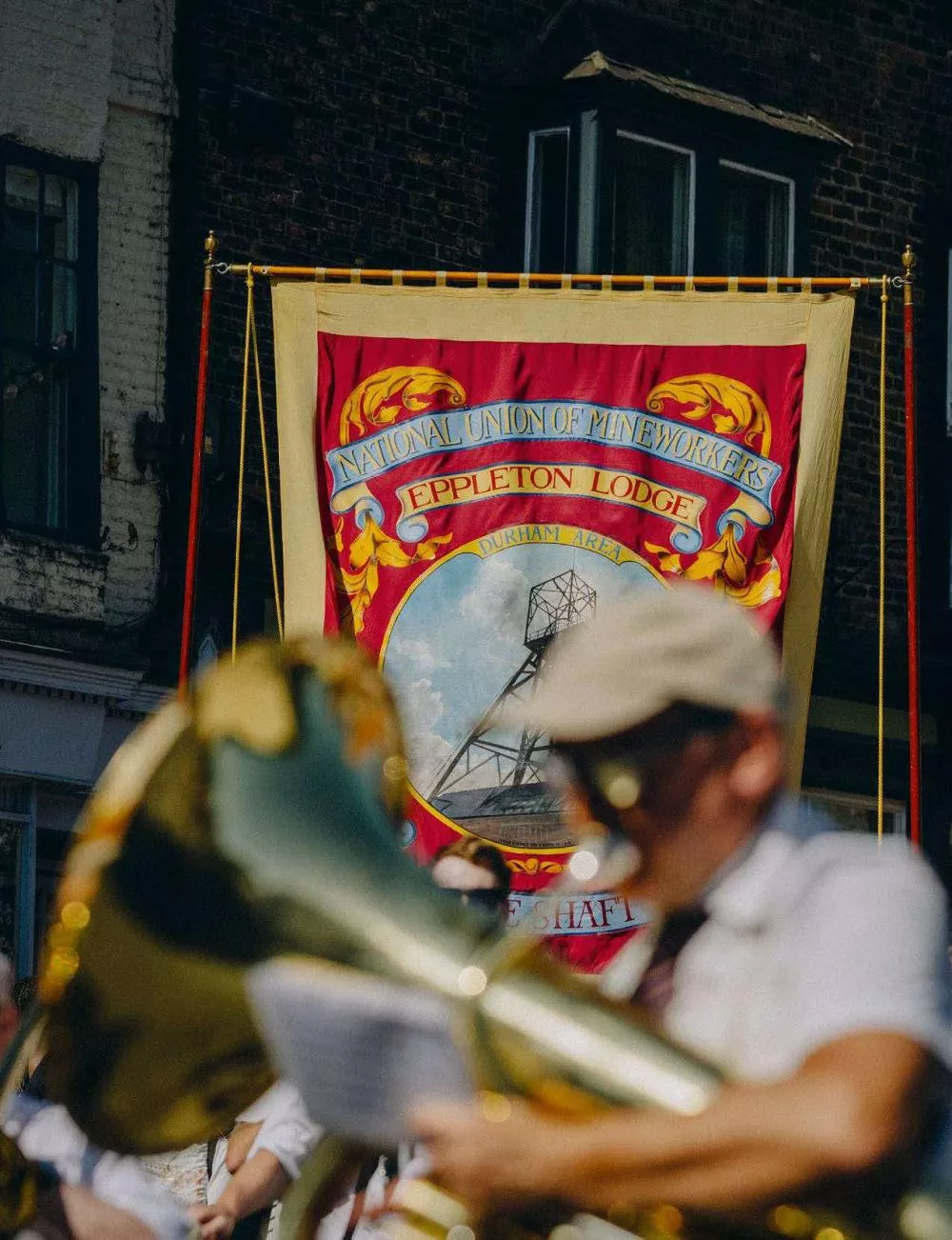 Une bannière de l'Union Nationale des Mineurs, section Eppleton Lodge, avec un musicien jouant d'un instrument à vent au premier plan.