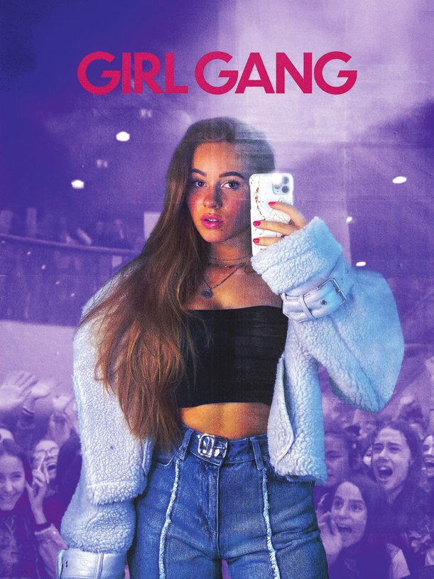 Une jeune femme prend un selfie avec son téléphone. Elle porte un haut noir, une veste en fourrure et un jean. En arrière-plan, une foule de personnes est visible. Le texte "GIRL GANG" est écrit en haut de l'image.
