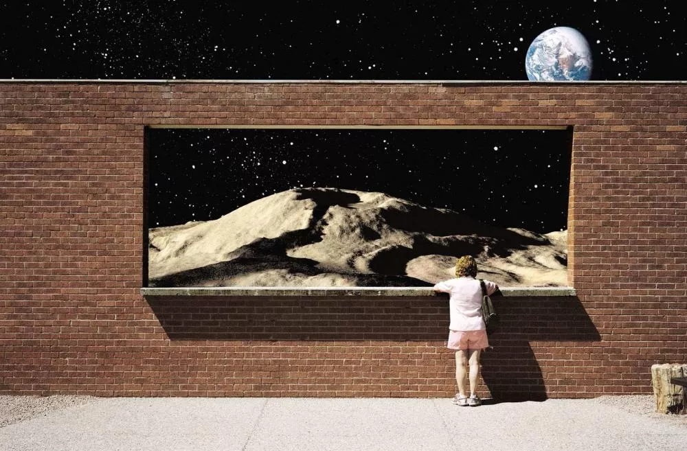 Une personne se tient devant un mur de briques avec une grande ouverture, regardant un paysage lunaire avec des étoiles et la Terre visible dans le ciel.