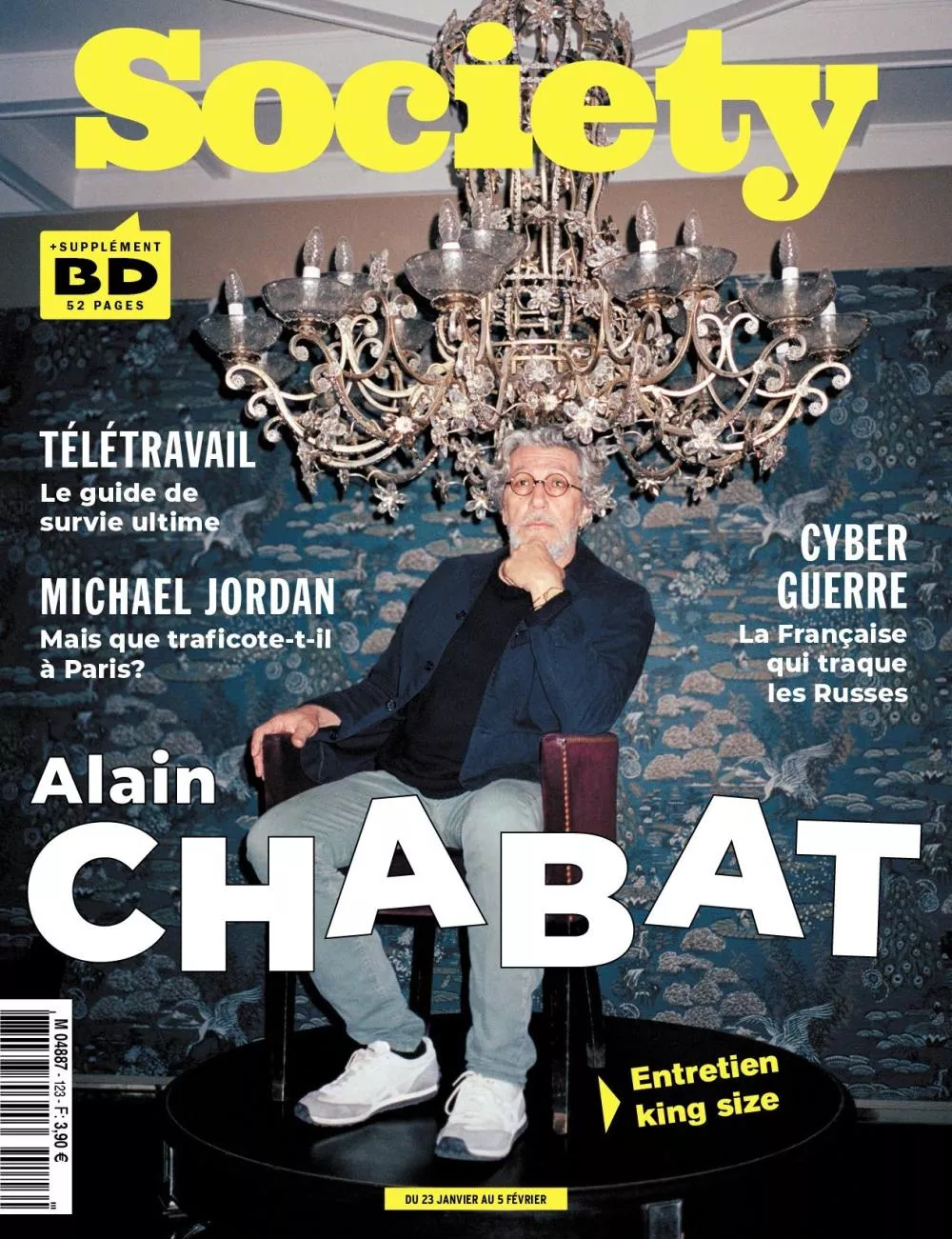 Un homme est assis sous un grand lustre, avec un fond de papier peint décoratif. Le texte mentionne des sujets comme le télétravail, Michael Jordan à Paris, et la cyber-guerre. Il y a un entretien avec Alain Chabat.