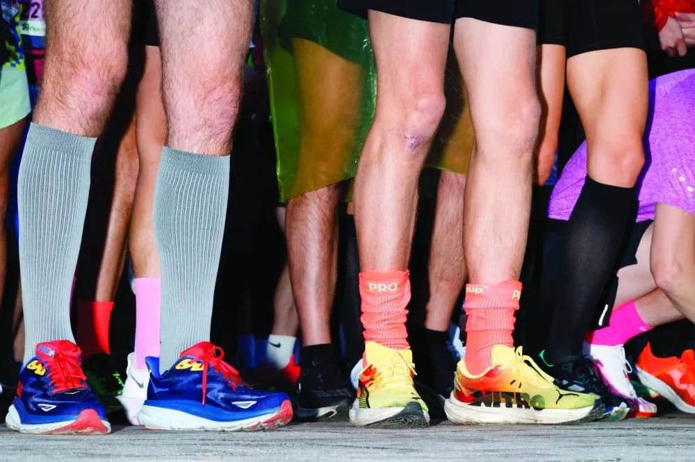 Des jambes de coureurs portant des chaussures de sport colorées et des chaussettes montantes.