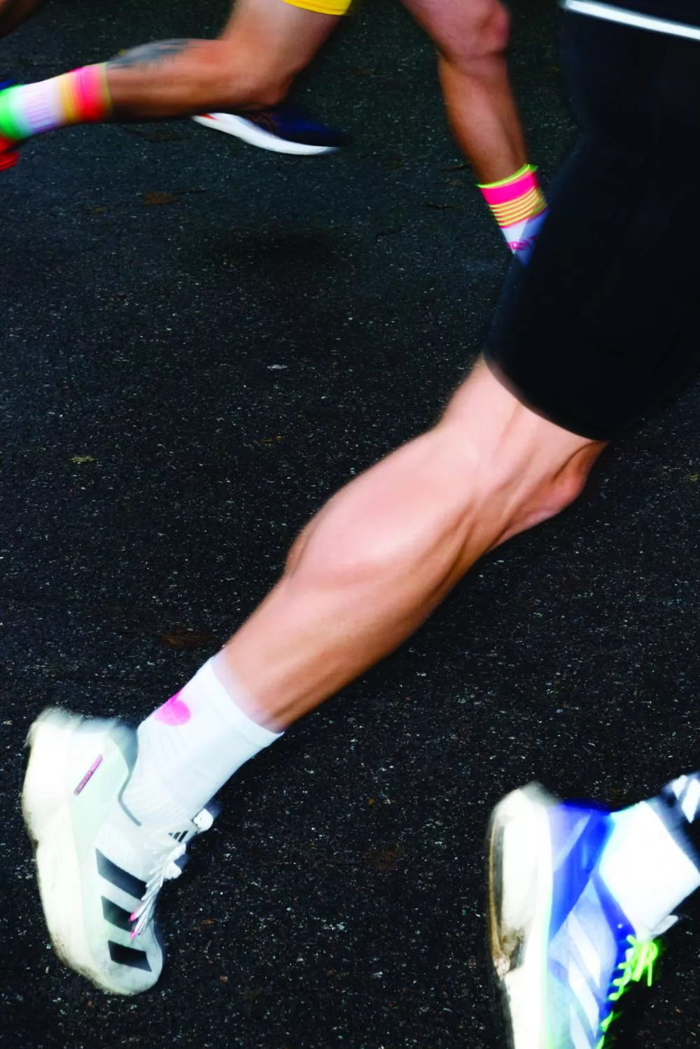 Un coureur en mouvement, focalisé sur ses jambes musclées, portant des chaussettes blanches et des chaussures de sport.
